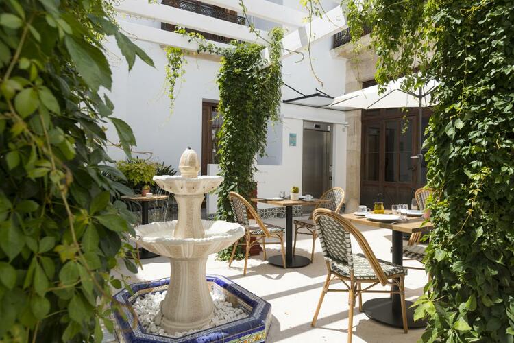 Patio interior de La Marsellesa con pérgola blanca, sillas y mesas para disfrutar al aire libre
